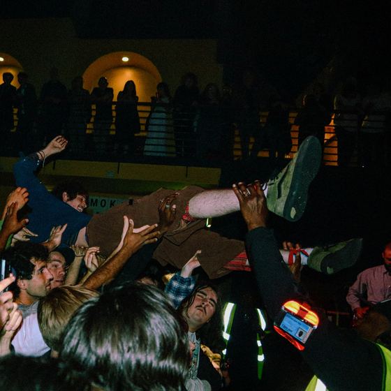 Crowd surfing at a concert, hands raised